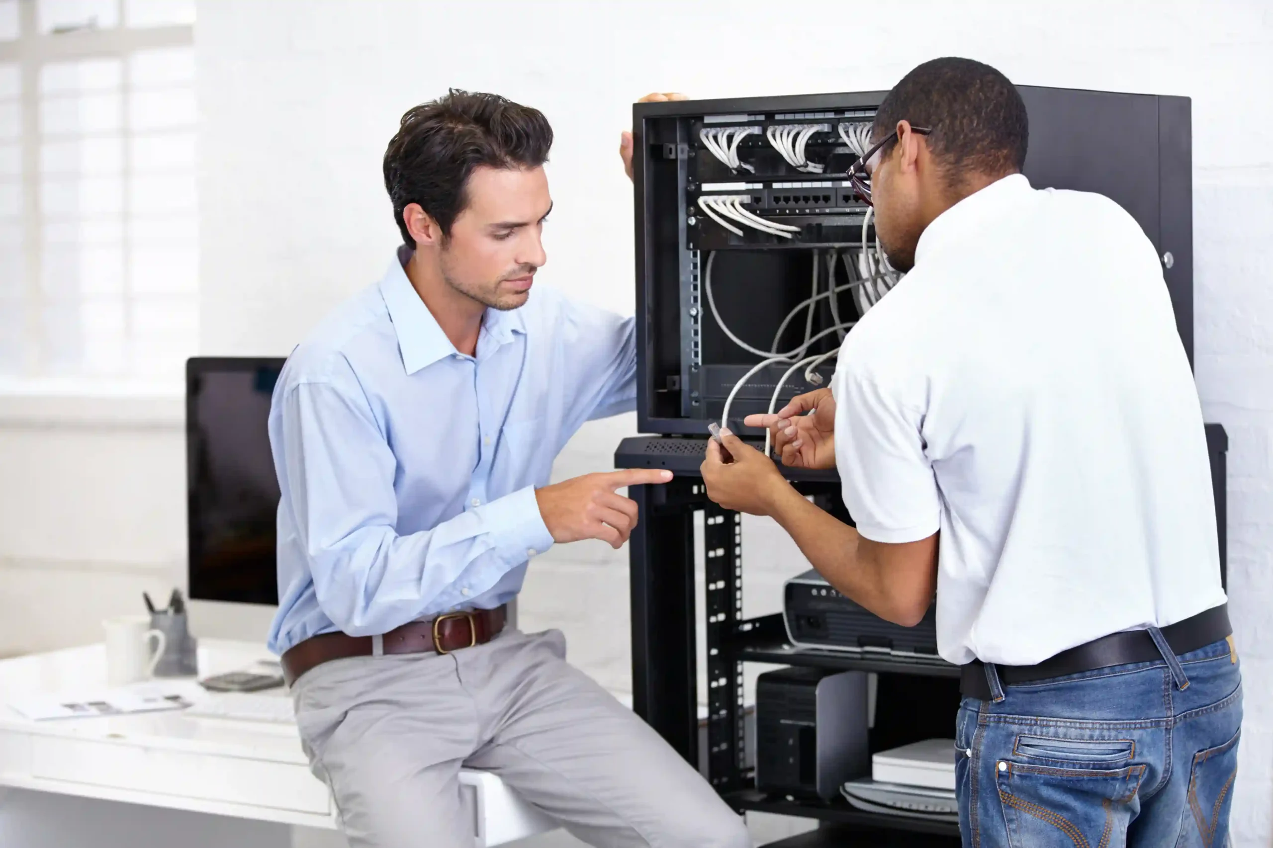 Two men working on a networking cabinet.