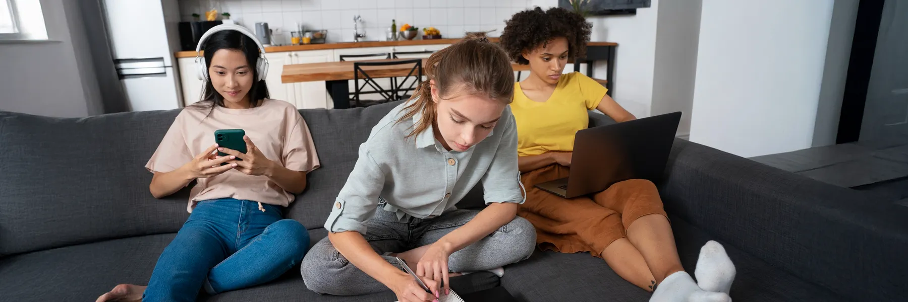 Three young women studying and relaxing on couch