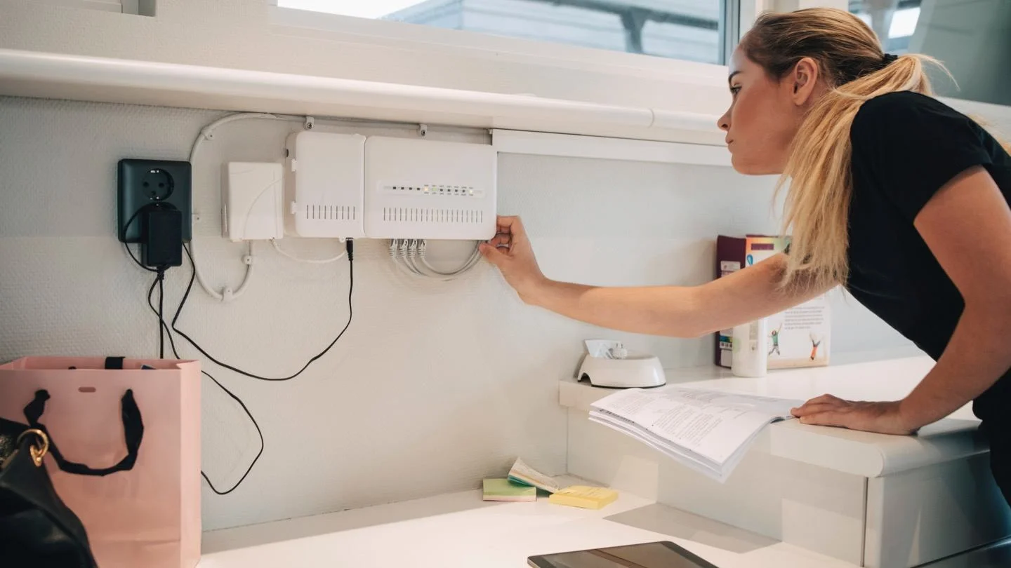 Person adjusting cables on a wall-mounted device.