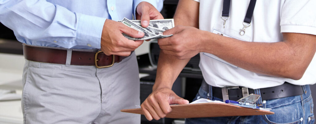 Two people exchanging cash and paperwork indoors.