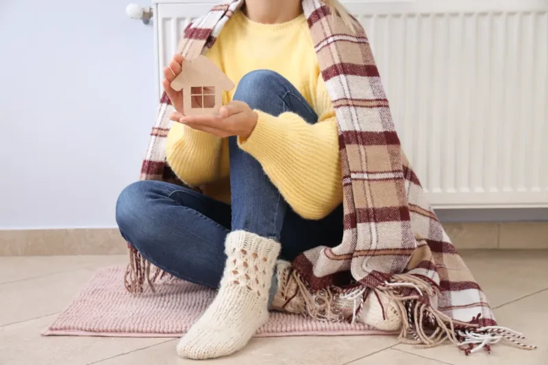 Person holding a small house model while cozy.