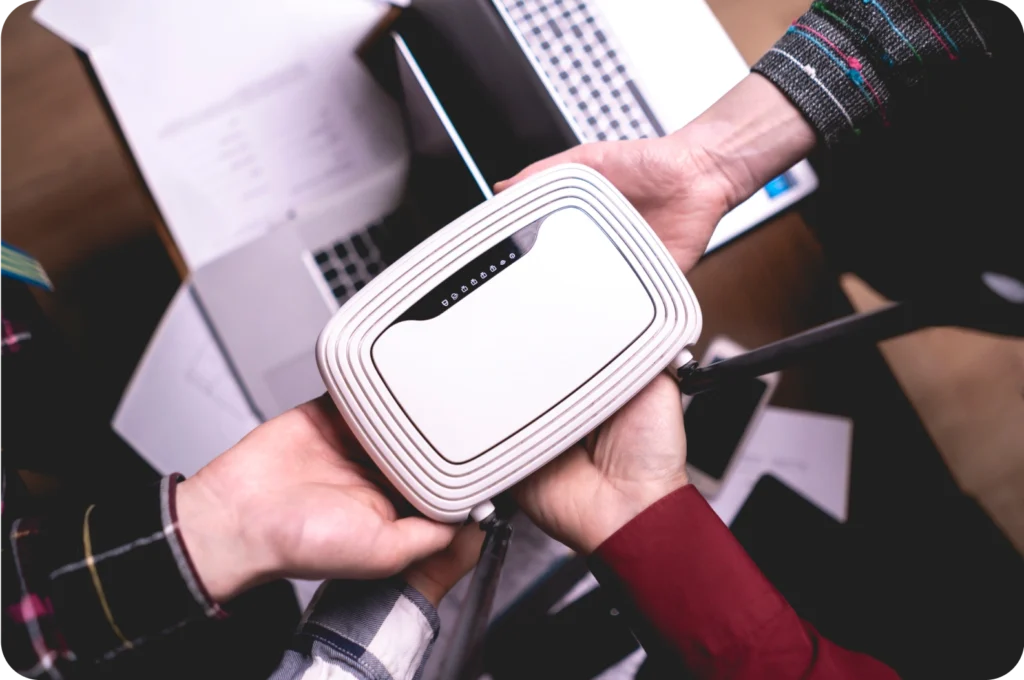 Two hands exchanging a wireless router.