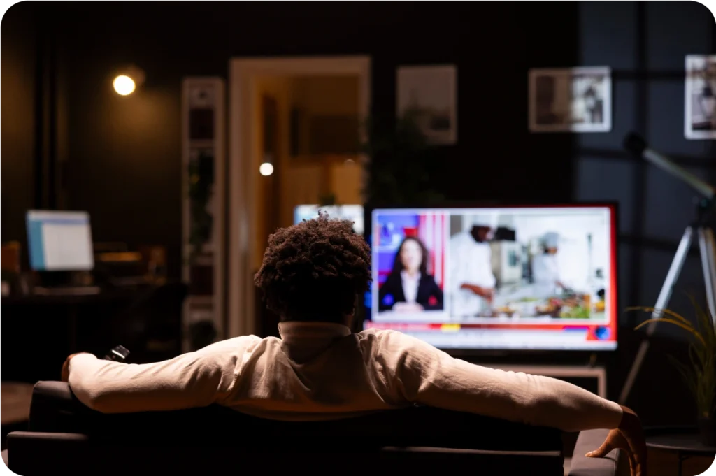 Person relaxing on couch watching television news