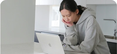 Person focused on laptop in modern kitchen.