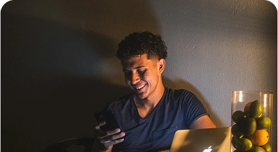 Person smiling while using phone and laptop